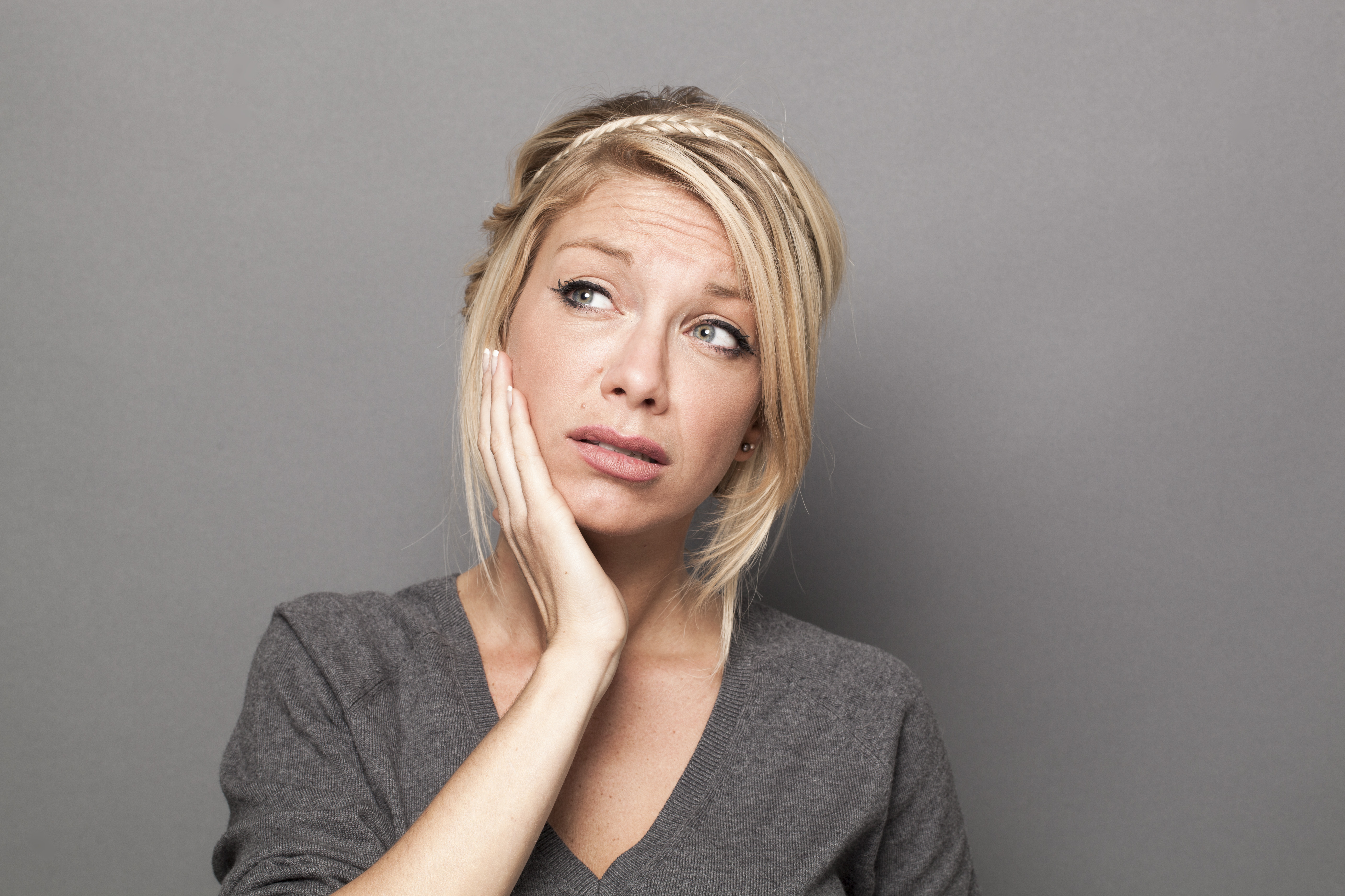 A Staten Island woman holding her jaw from tooth pain in need of an emergency tooth extraction