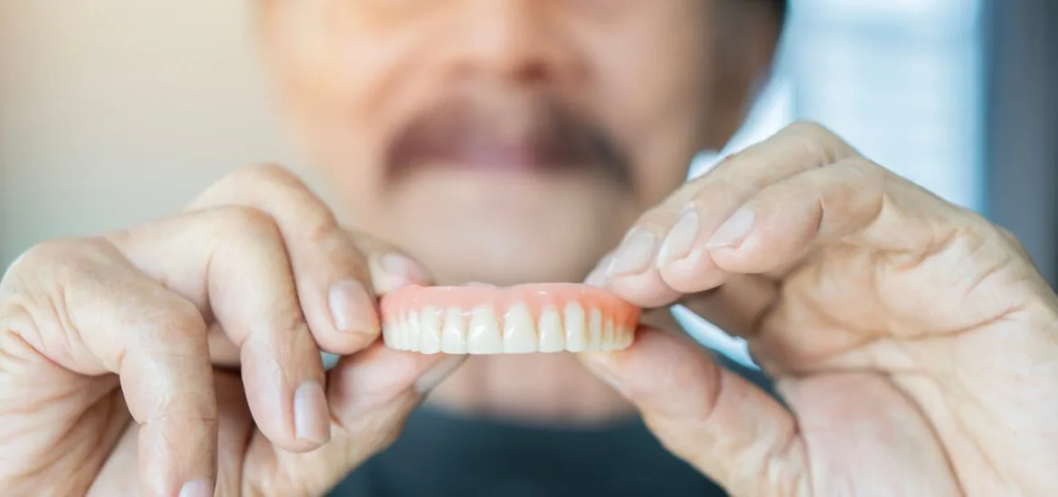 older man holding up his dentures in Staten Island