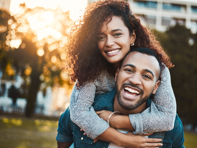 Happy couple, piggyback and portrait outdoor,s laughing and smiling, healthy teeth